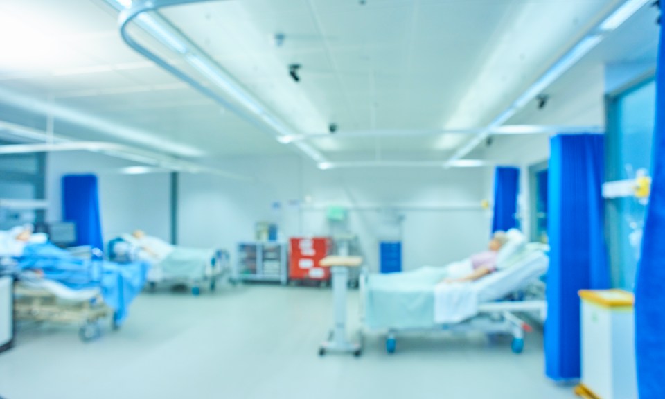 Blurred image of an empty hospital room with beds.