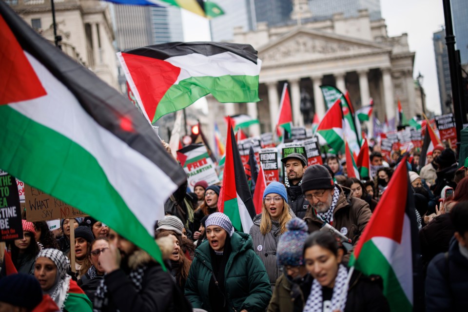 Pro-Palestinian protesters marching in London, holding signs and Palestinian flags.