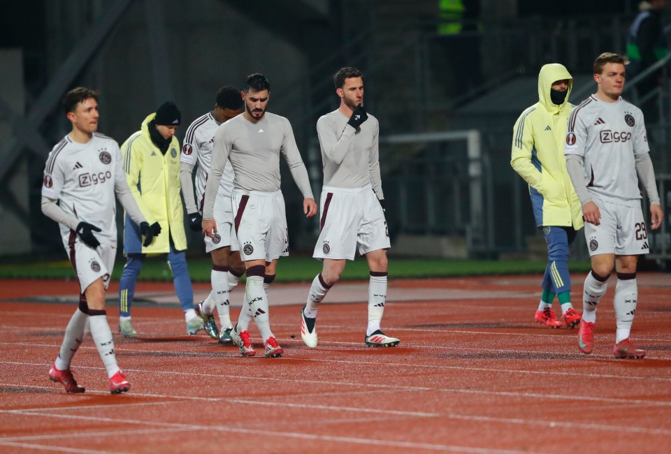 Ajax Amsterdam players walking off the field after a loss.