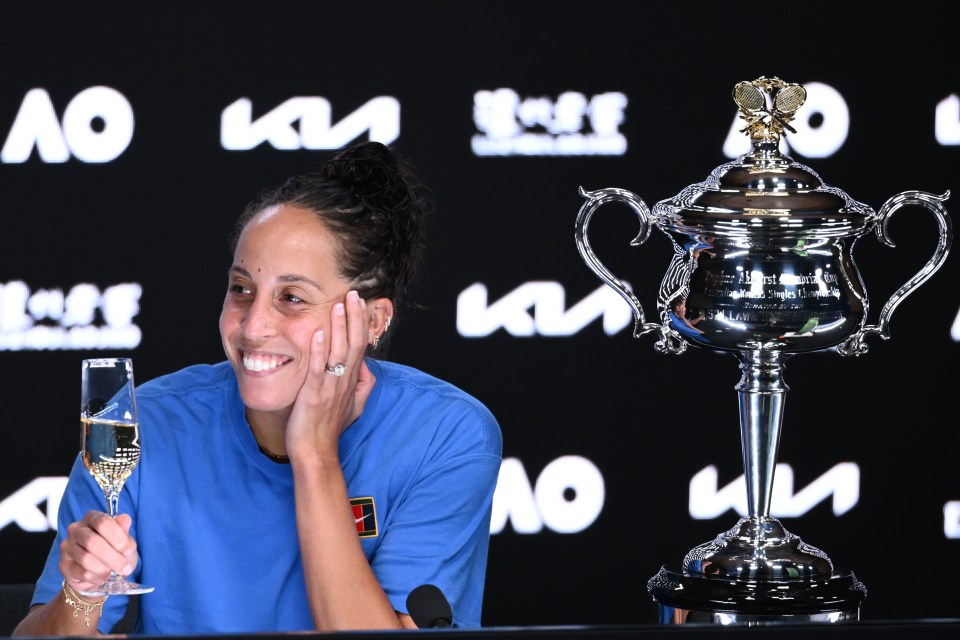 Madison Keys at a press conference after winning the Australian Open, holding a glass of champagne.