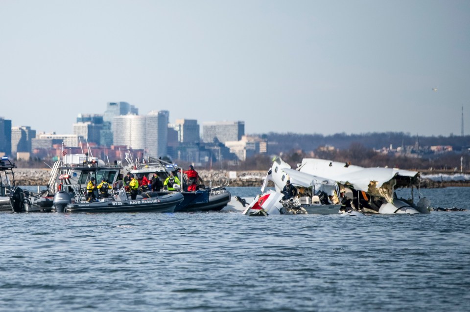 Wreckage of a plane and helicopter in the Potomac River with rescue boats.