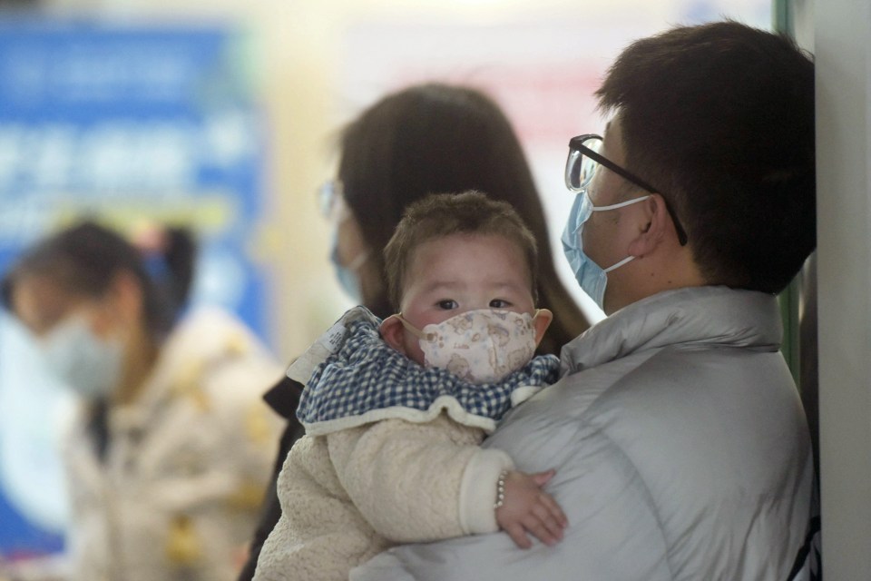 Baby wearing a face mask in a hospital with family.