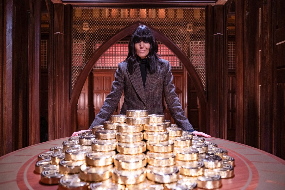 Claudia Winkleman on the set of The Traitors, with a large pile of gold coins.