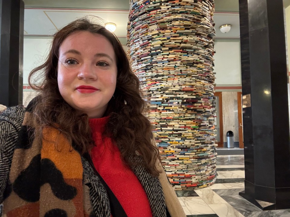 Woman taking a selfie in front of a book sculpture.