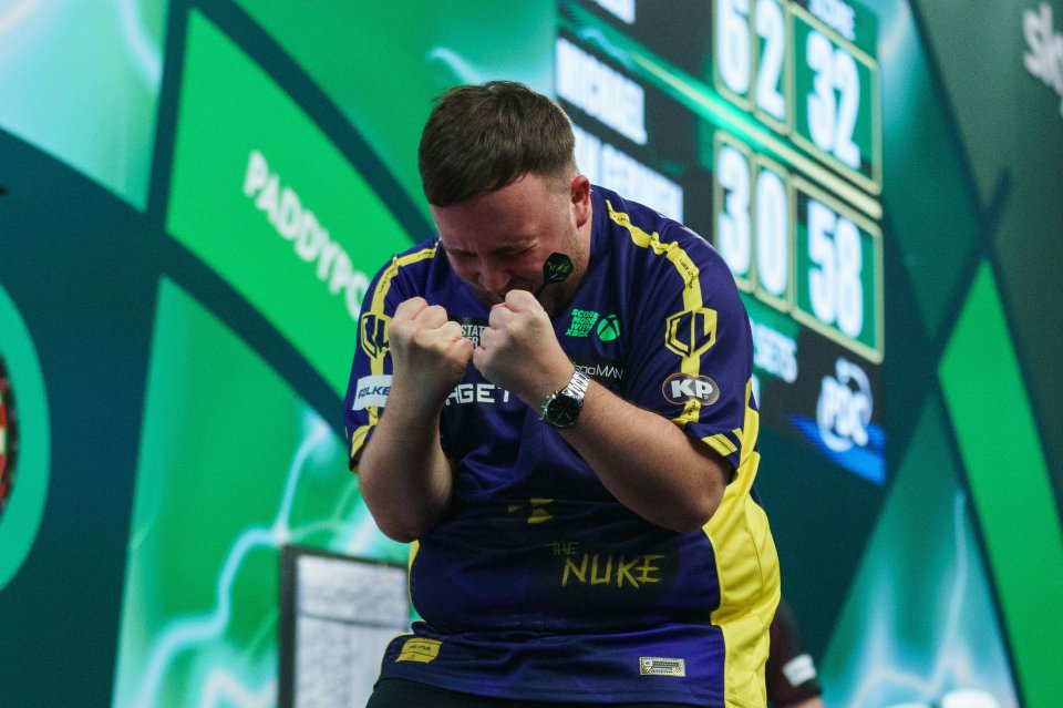 Luke Littler holding the Sid Waddell Trophy after winning a darts championship.