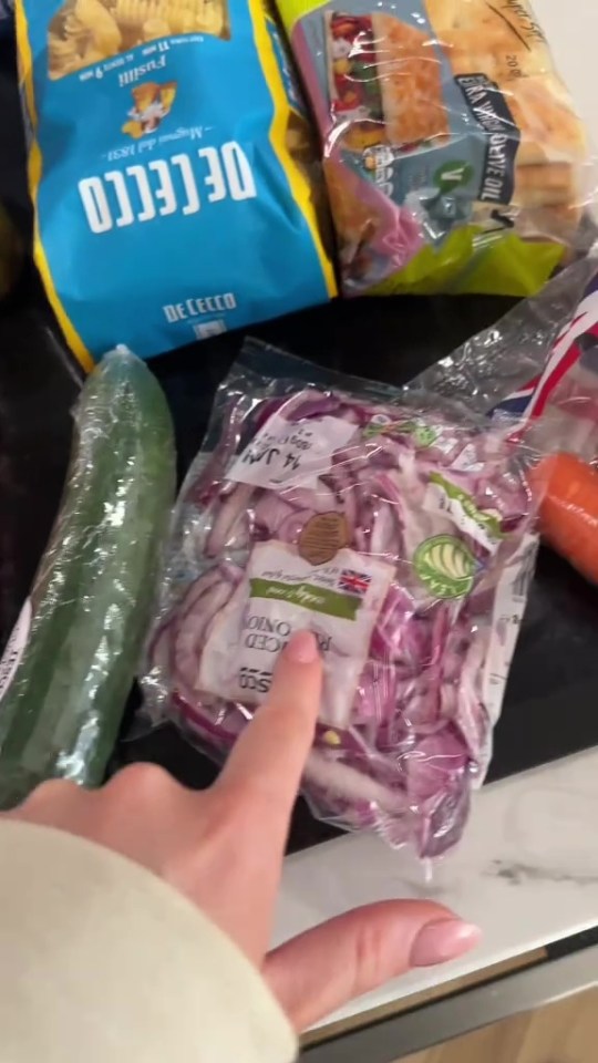 Grocery items including pasta, bread, cucumber, and sliced red onions.