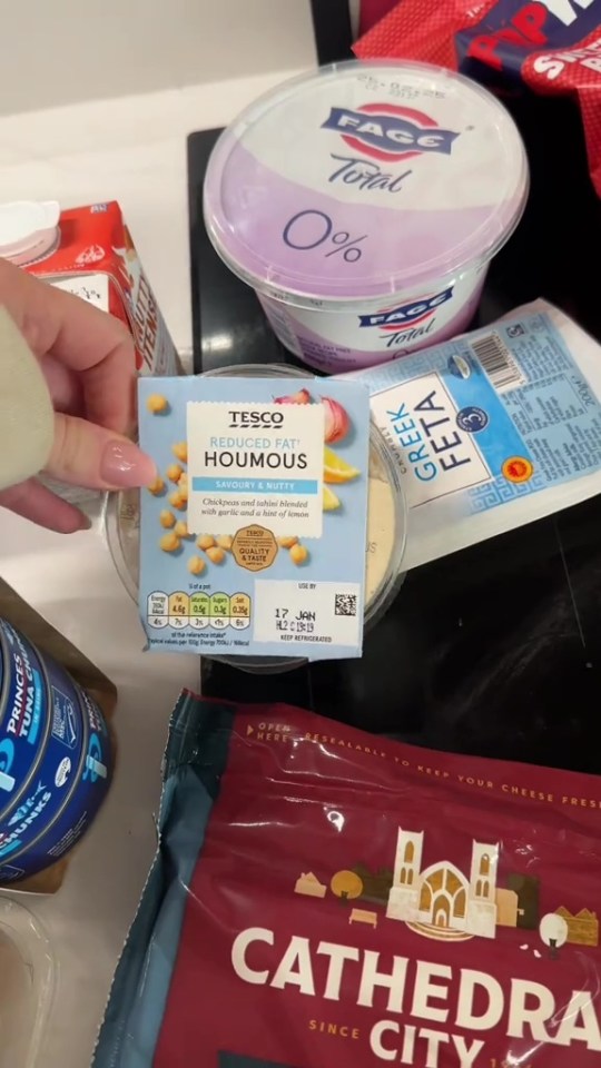 Grocery shopping haul including hummus, yogurt, and feta cheese.