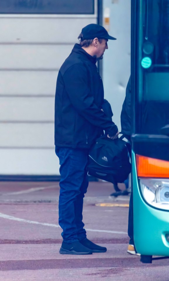 Peter Kay, carrying a bag, near a tour bus.