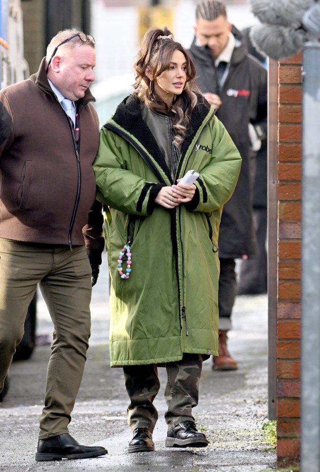 Michelle sported bouncy curls and wrapped up in a green coat on set