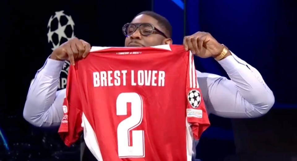 A man holding up a Brest soccer jersey.