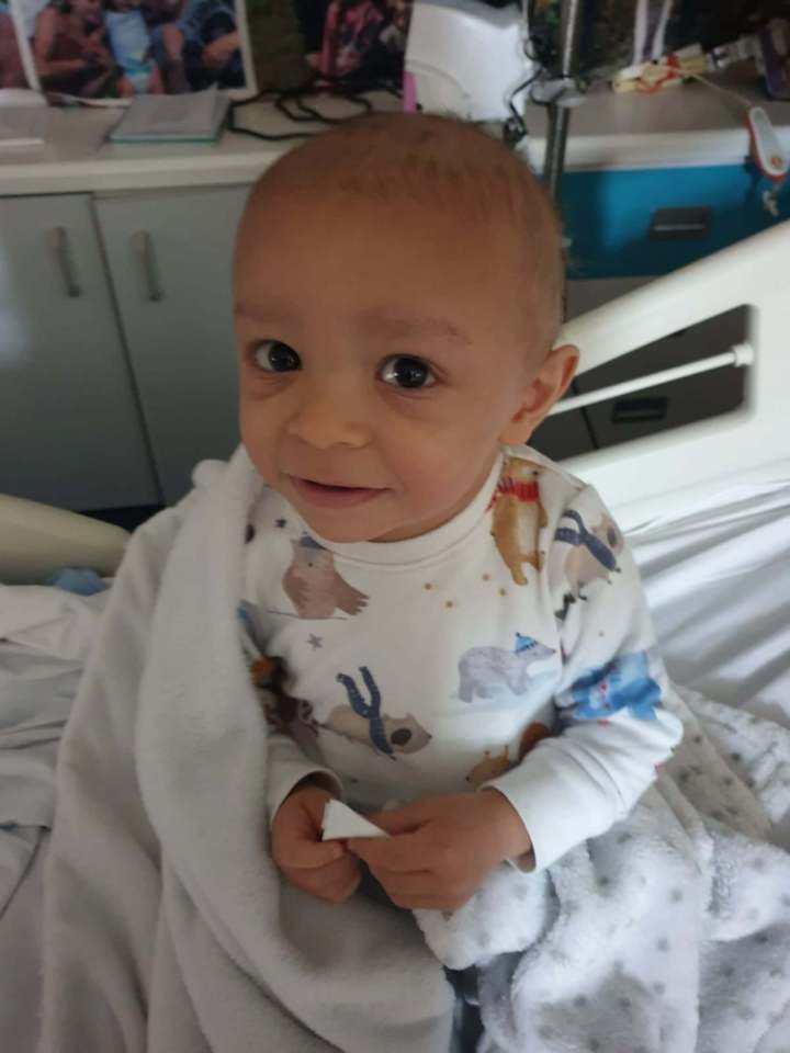 Young boy with little hair sitting in a hospital bed.