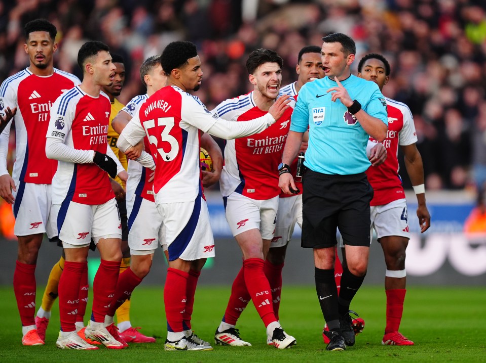 Referee Michael Oliver surrounded by Arsenal players.