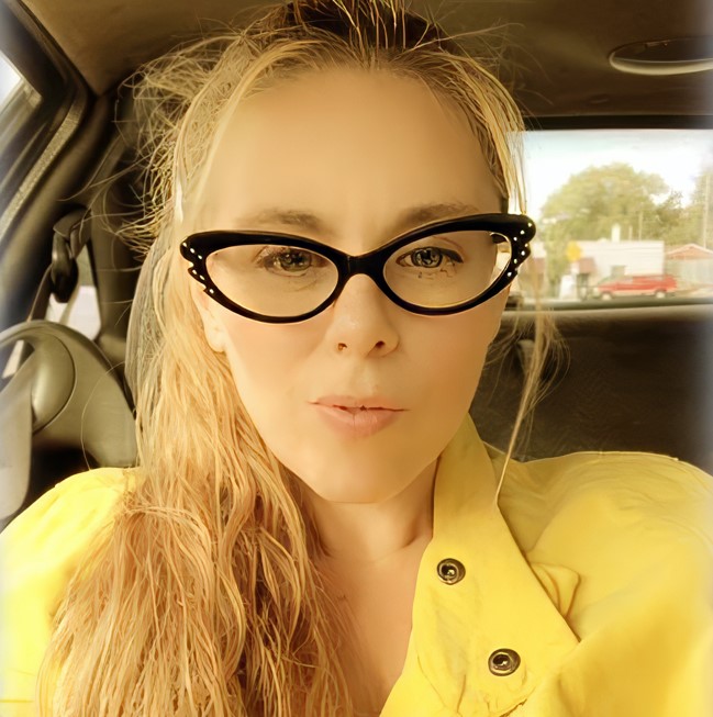 Aimee Betro, alleged hitwoman, in a yellow jacket and cat-eye glasses.