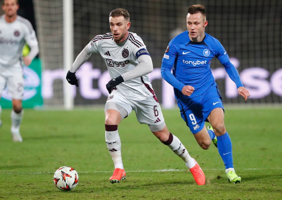 Soccer players Jordan Henderson and Janis Ikaunieks competing on a soccer field.