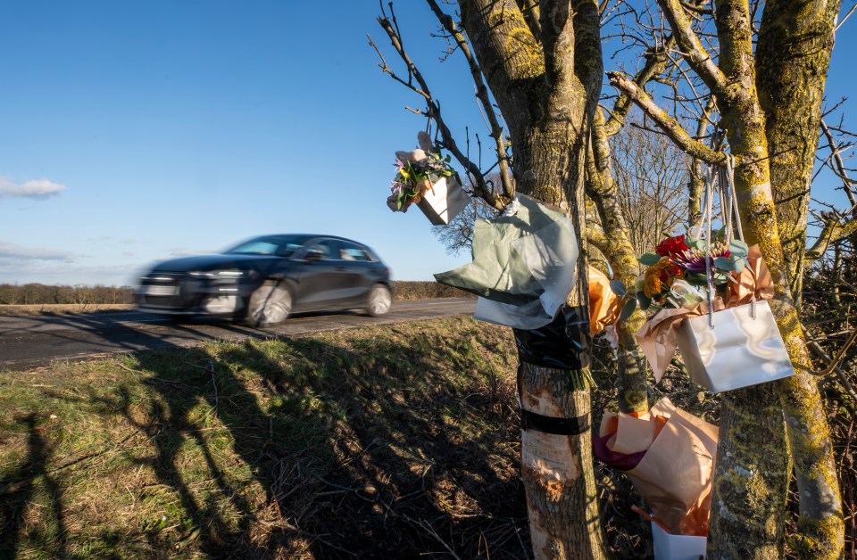 Floral tributes on a tree near a road where a car accident occurred.