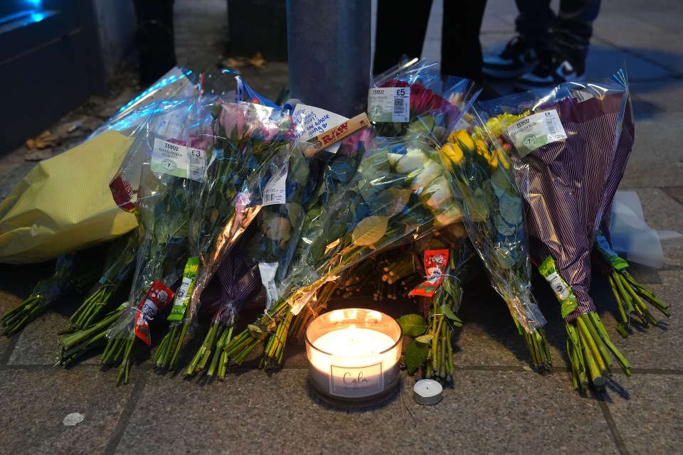 Floral tributes and a candle at a memorial.