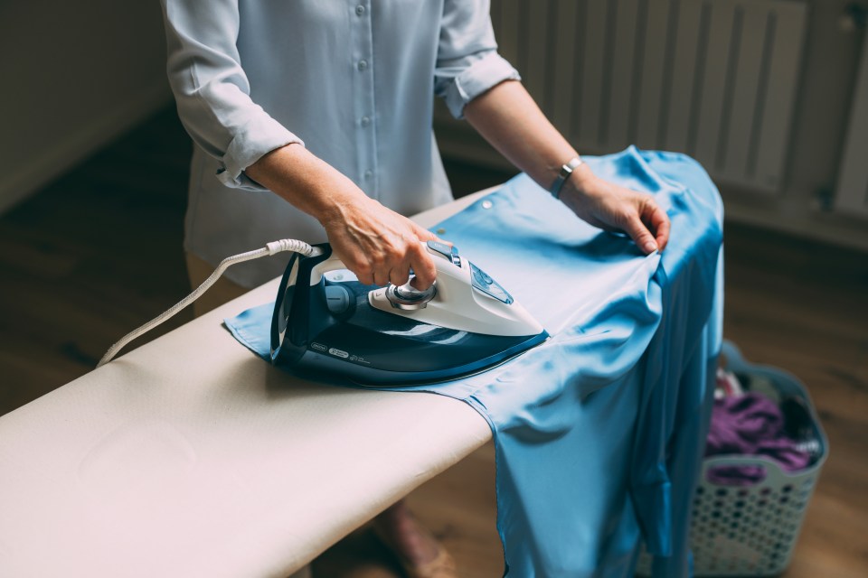 Woman ironing a blue shirt.