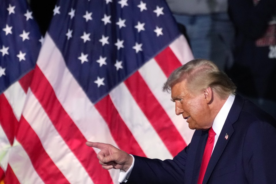 Former President Trump pointing in front of American flags.