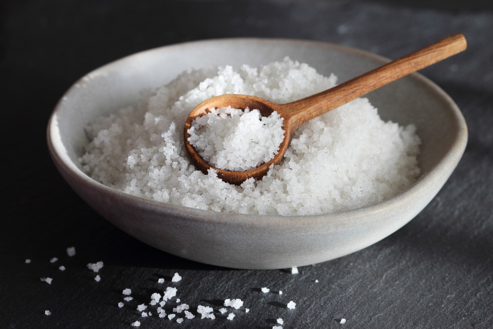 Sea salt in a grey bowl with a wooden spoon.