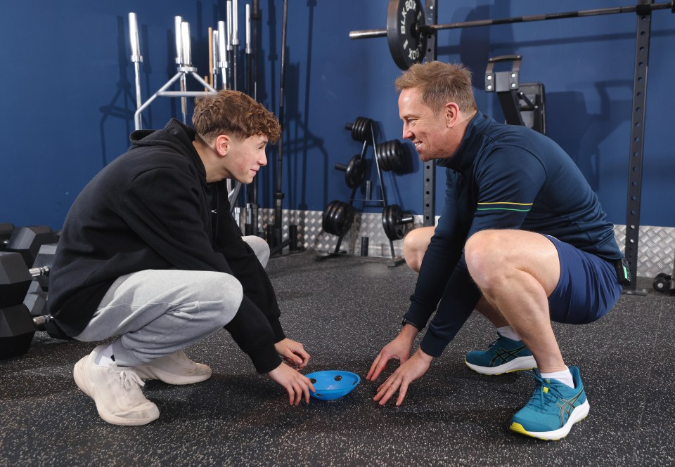 A father and son crouching in a gym, participating in a reaction time test.