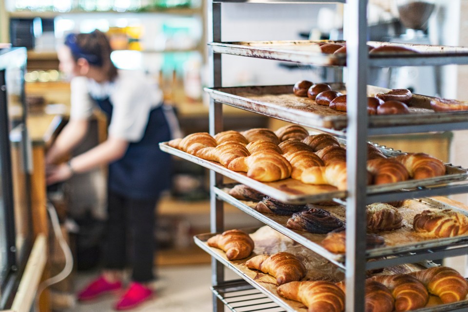 Croissants and other pastries cooling on racks in a bakery.