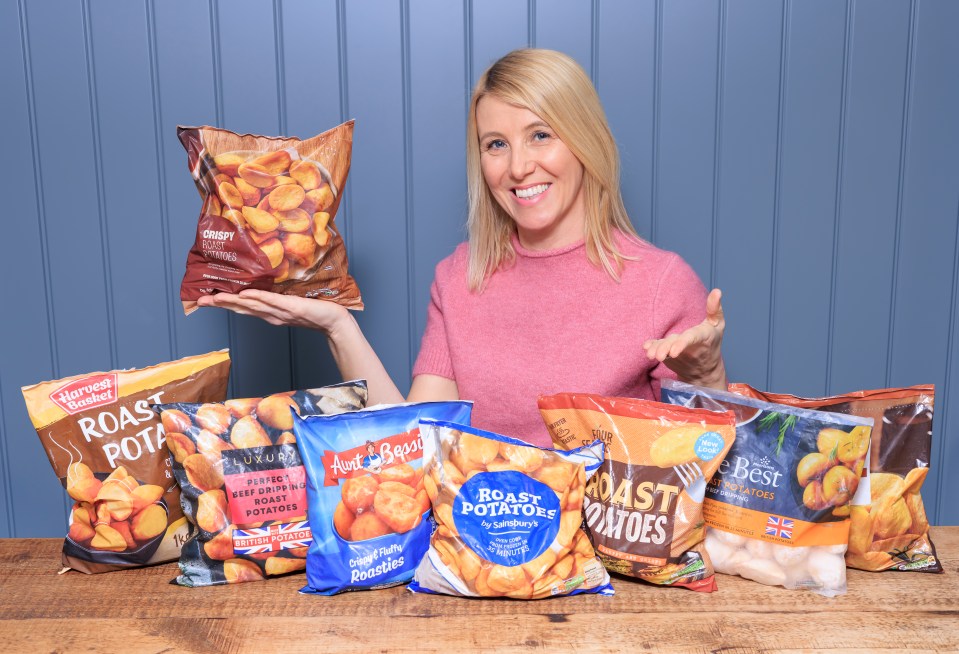 Woman holding and showing various brands of frozen roast potatoes.