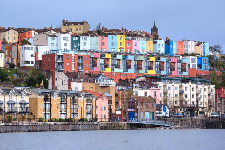 Colorful houses and apartments on a hill overlooking a river.