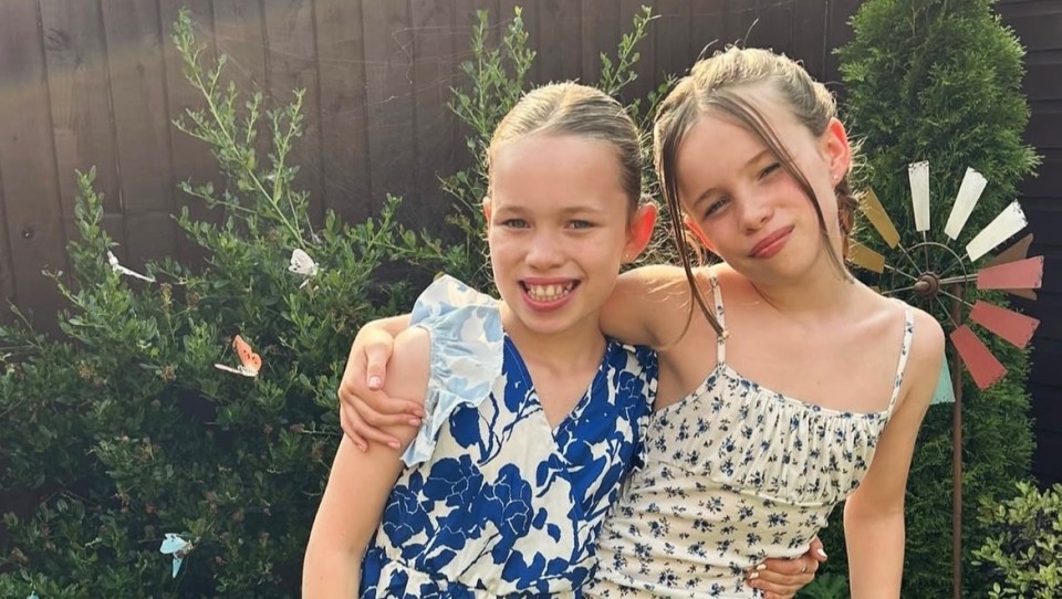 Two young girls hugging in a garden.