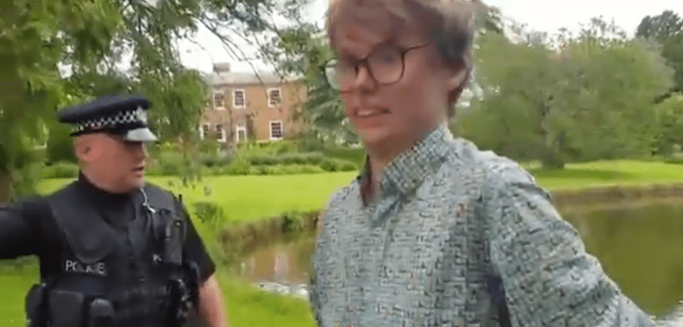 Oliver Clegg, a grinning protester, being questioned by a police officer.