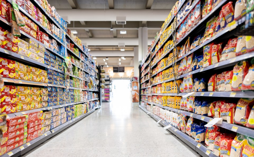 Supermarket aisle with shelves stocked with various food items.