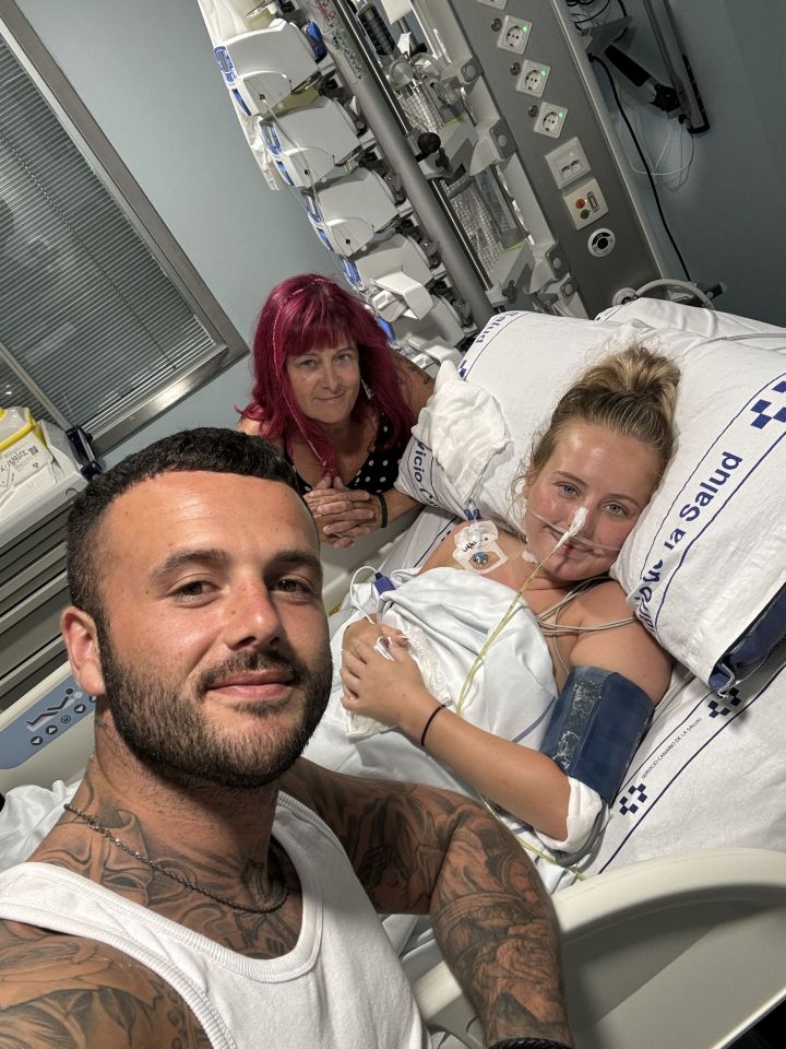 A young woman in a hospital bed with her partner and mother.