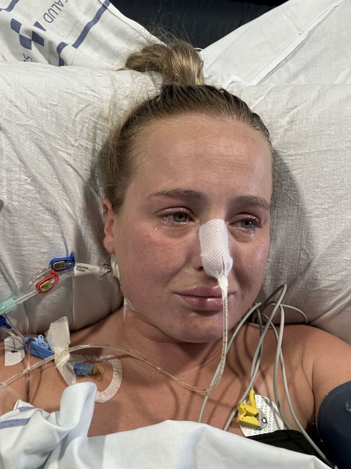 Woman in hospital bed crying with medical tubes.