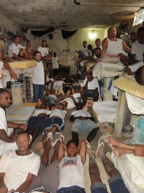 Overcrowded prison cell with many inmates.