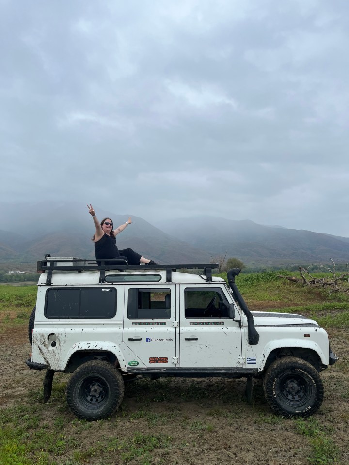 Woman sitting on top of a muddy Land Rover Defender in Halkidiki.