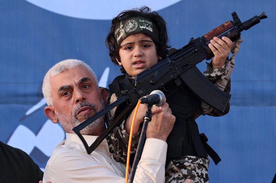 Yahya Sinwar holding a child with a rifle.