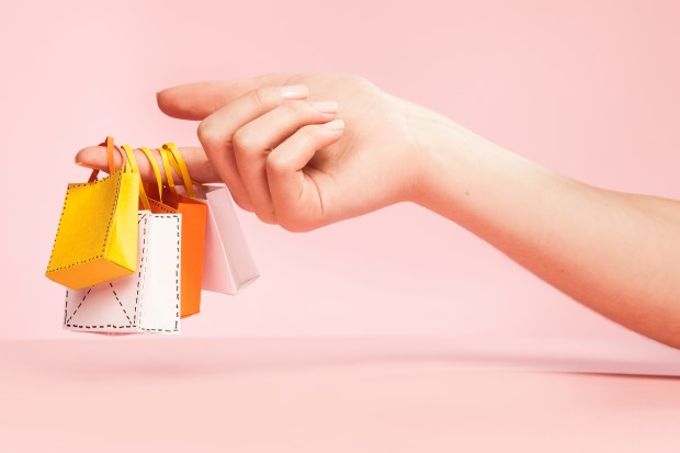 Woman's hand holding miniature shopping bags.