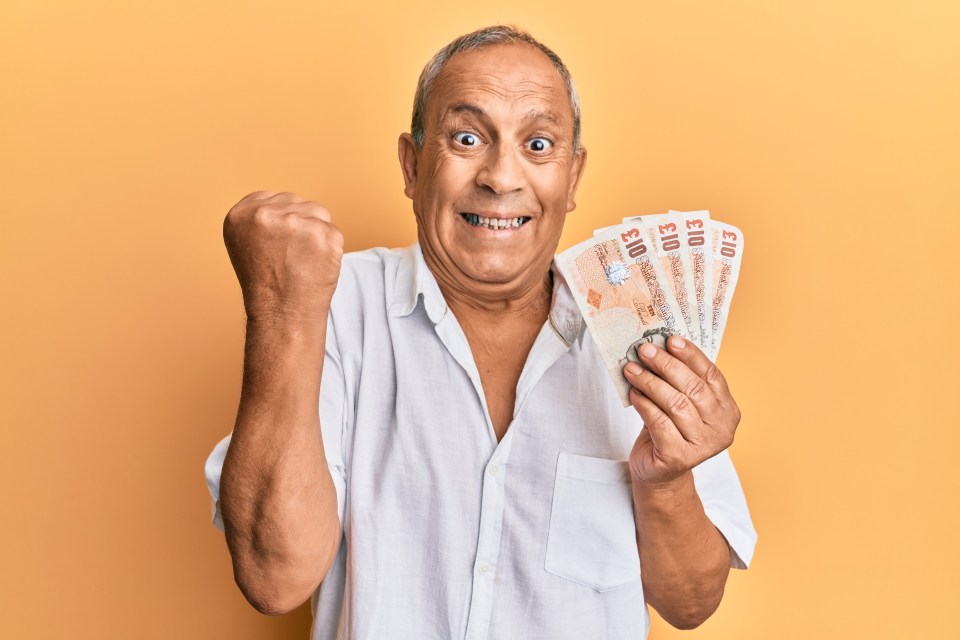 A jubilant man holding several British ten-pound notes.