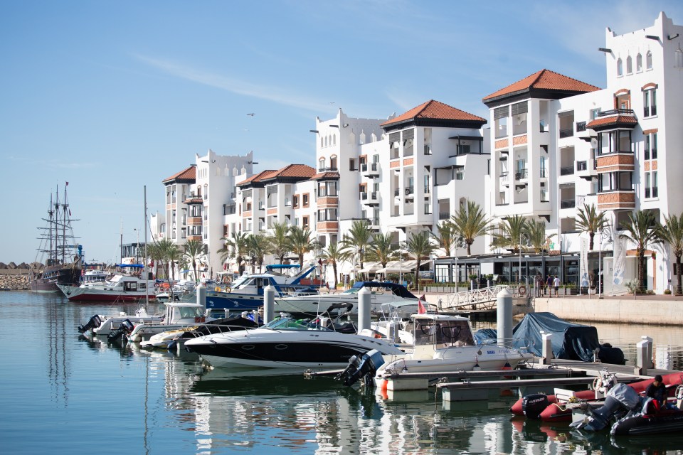 Agadir harbor with boats moored alongside white buildings.