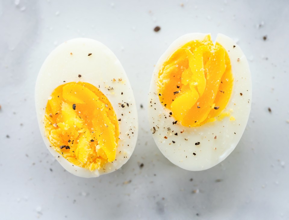 Two halved hard-boiled eggs seasoned with salt and pepper.