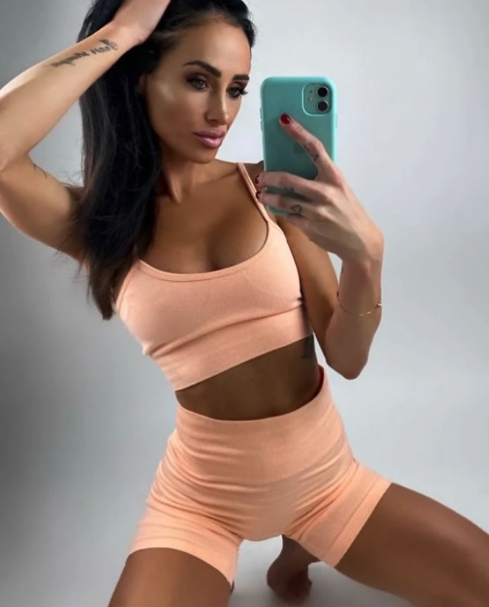 Woman in peach-colored athletic wear taking a selfie.