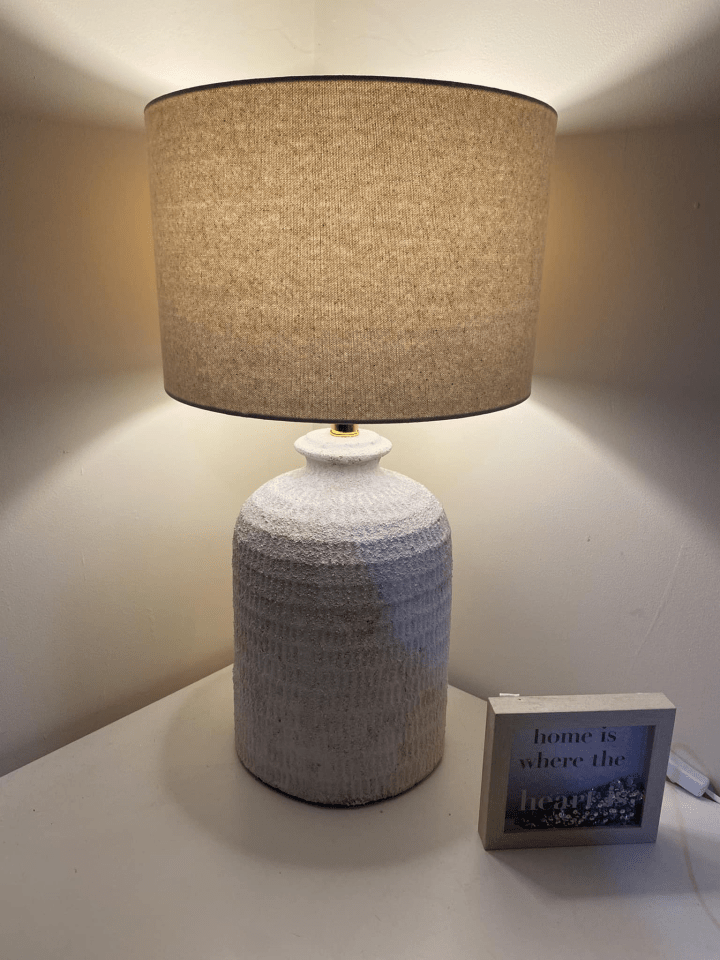 Table lamp with beige shade and textured white base.