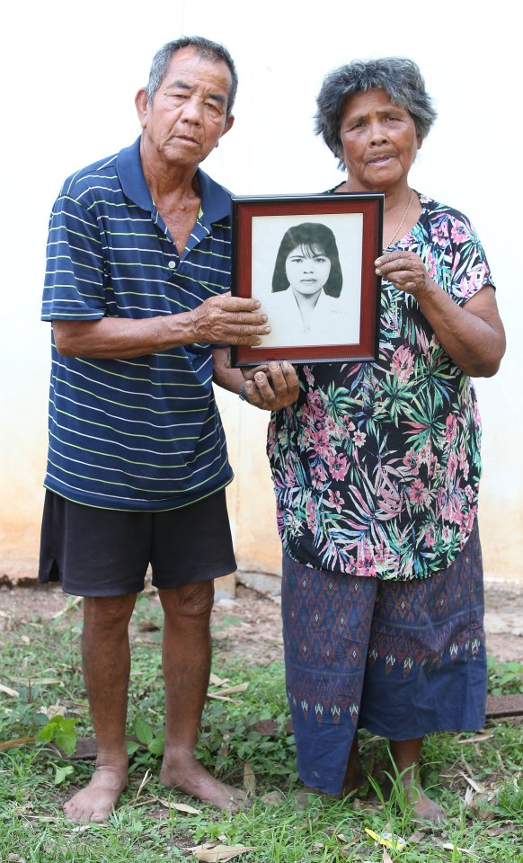 Older couple holding a framed photo of their daughter.