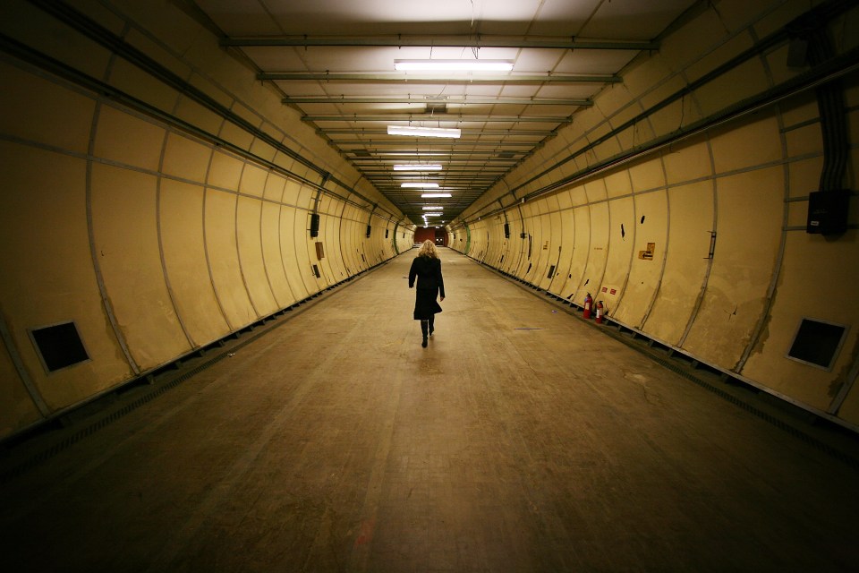 Person walking down a long, dimly lit tunnel.