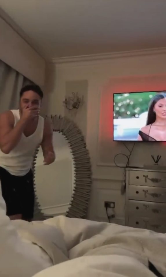 Man reacting to a TV screen showing a woman.