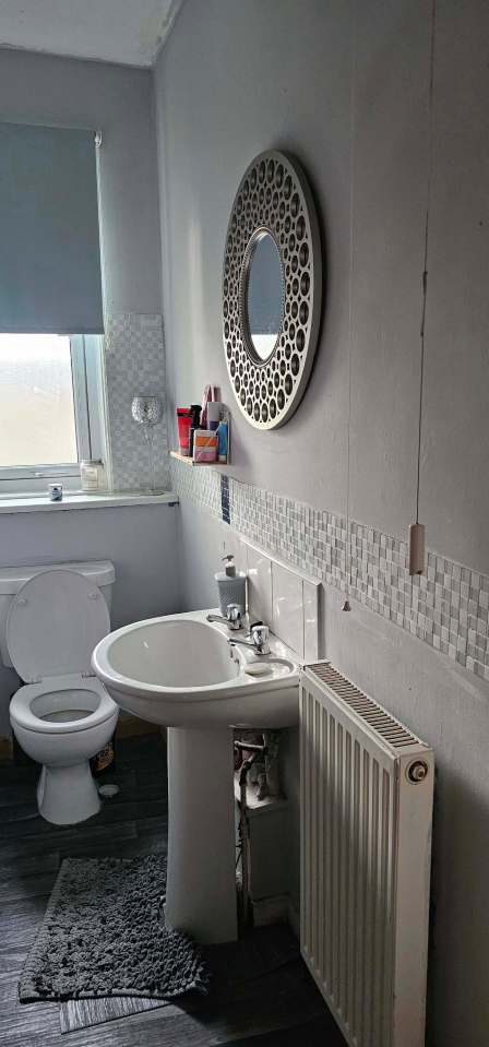 Bathroom makeover with new sink, toilet, mirror, and flooring.