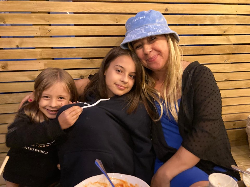 A mother and her two daughters smiling for a photo.