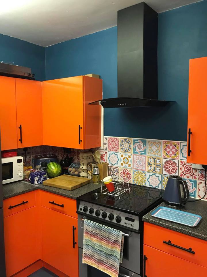 Orange kitchen with teal walls and patterned backsplash.