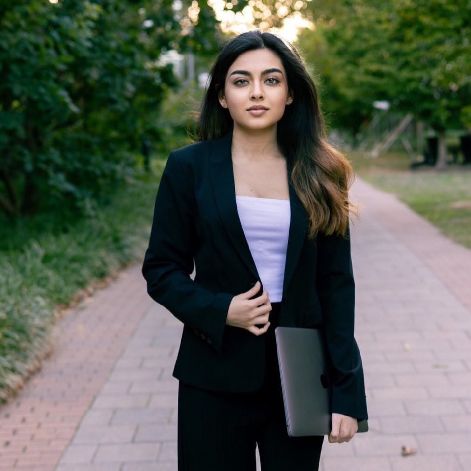 Woman in business suit holding a laptop.