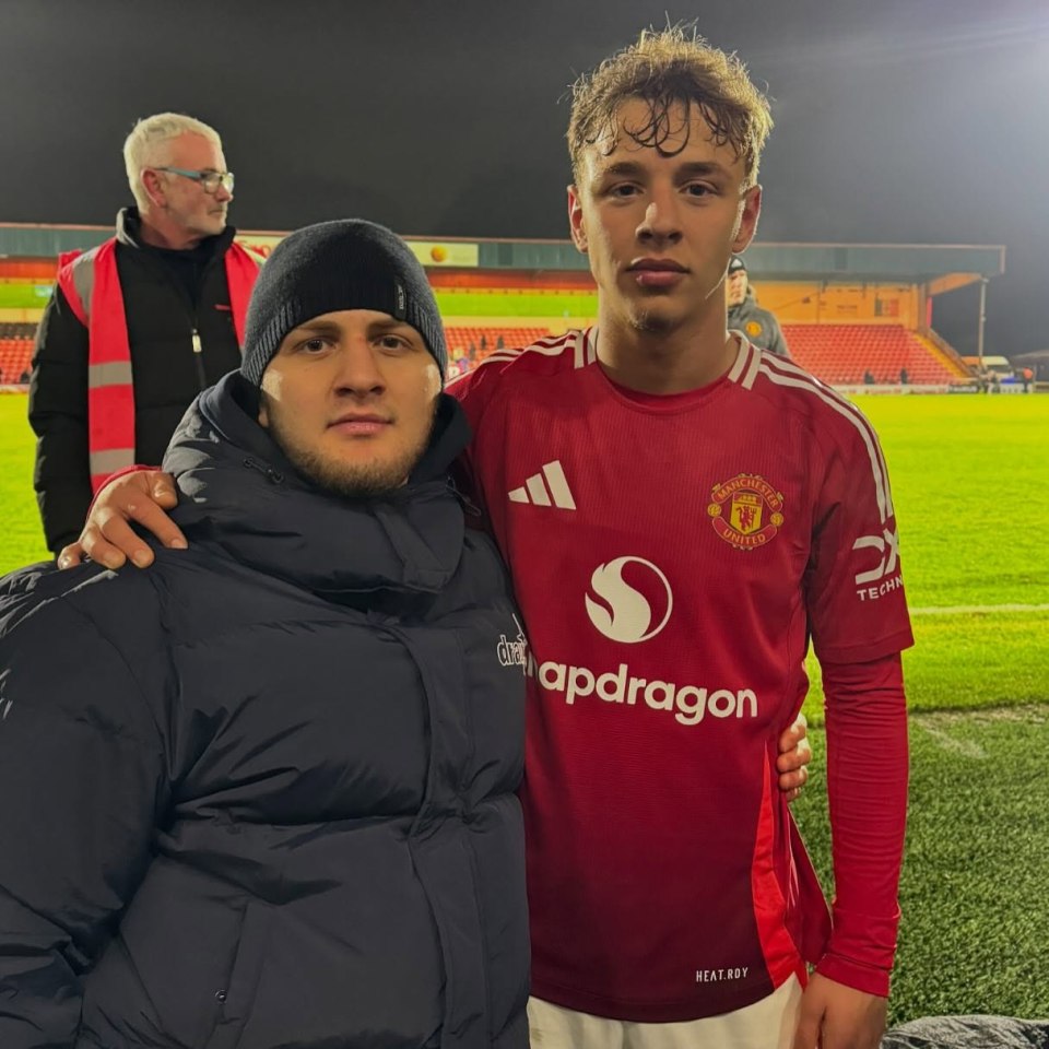 Two men at a soccer field; one in a Manchester United jersey.