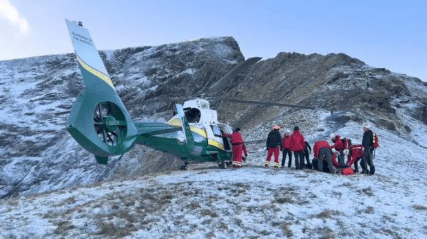 Mountain rescue team attending to a casualty near a helicopter.